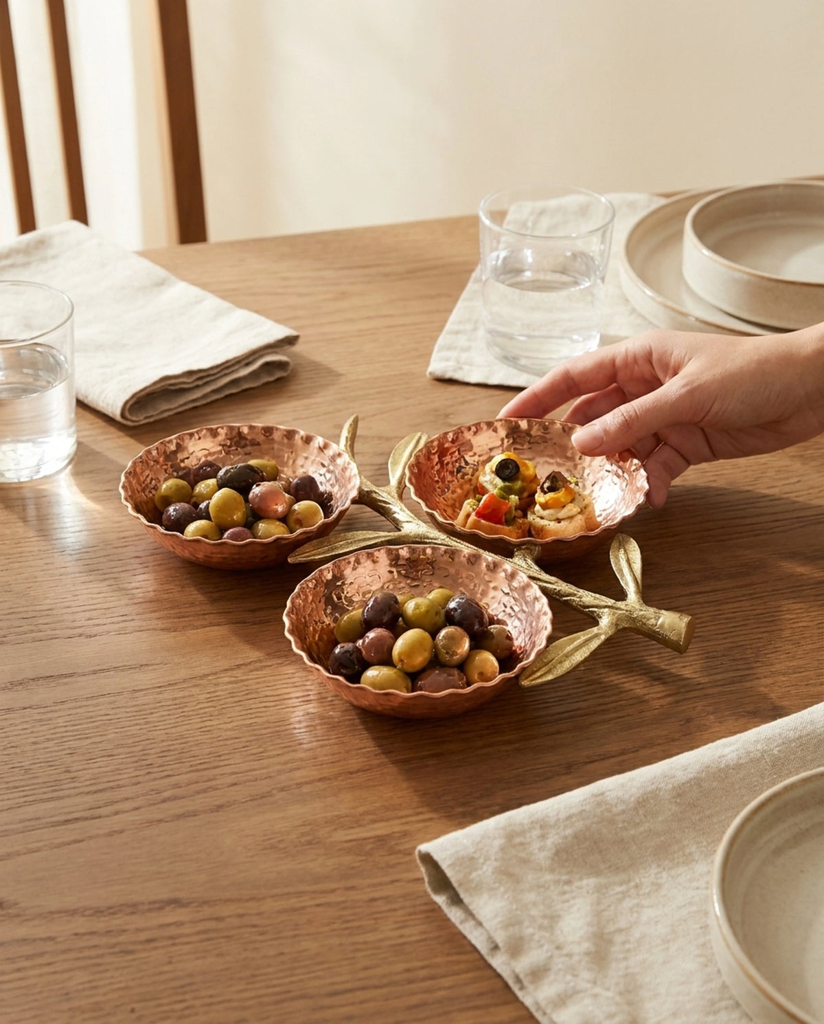 Zeytin ve meze çeşitleri servis edilen, ahşap masa üzerinde sofrada kullanıma hazır üçlü bakır sunumluk. - Gaziantep Bakırcılık