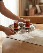 İki ince belli bardakta çay ve lokumlukla birlikte gümüş renkli el dövmesi bakır tepsi elde taşınırken - Gaziantep Bakırcılık