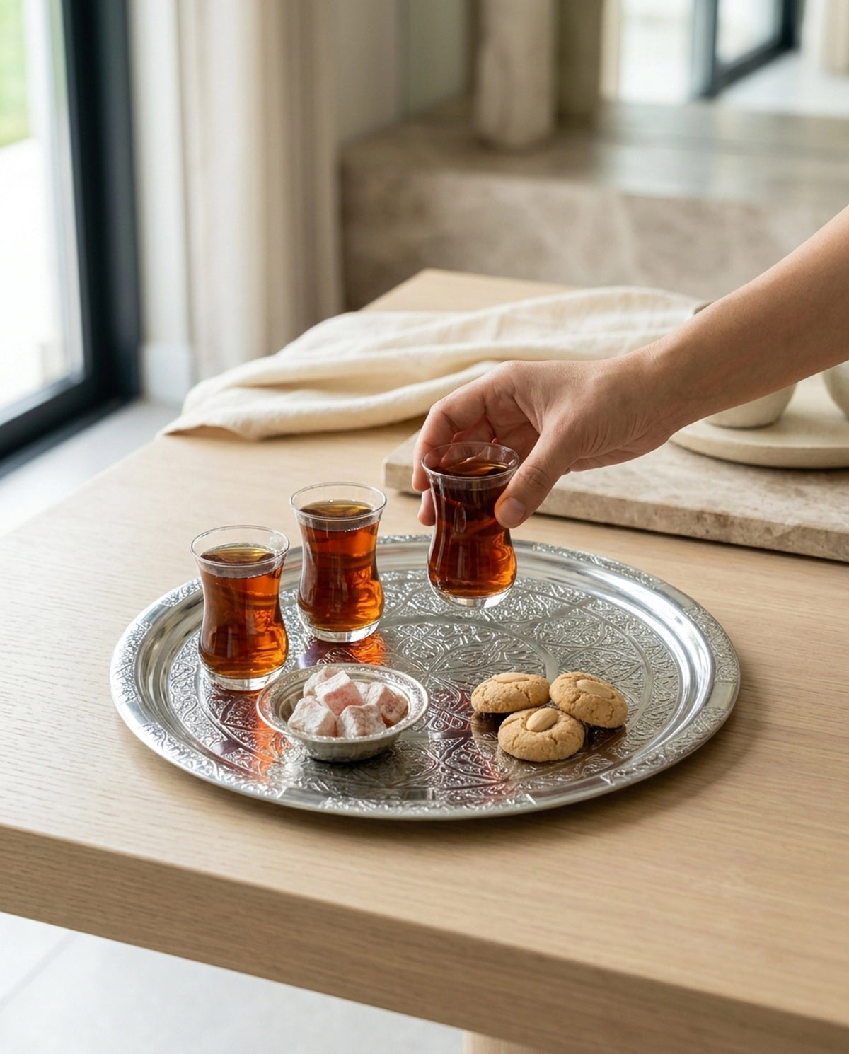 Üzerinde çay dolu bardaklar, lokum ve kurabiye olan çelik tepsiden çay alan bir el görünümü. - Gaziantep Bakırcılık