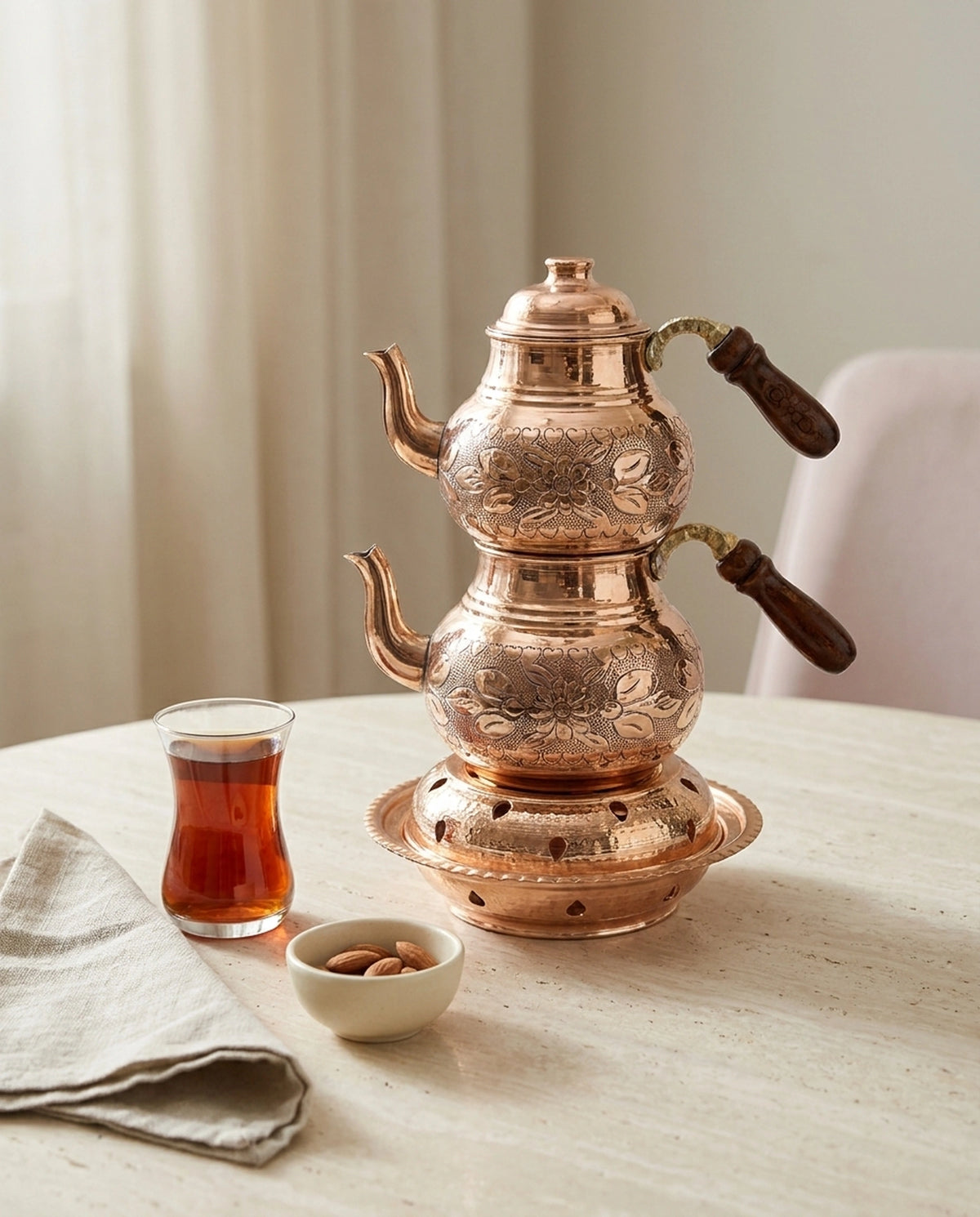 Ahşap masada çay bardağı ve atıştırmalık eşliğinde sunulan reşolu bakır çaydanlık. - Gaziantep Bakırcılık