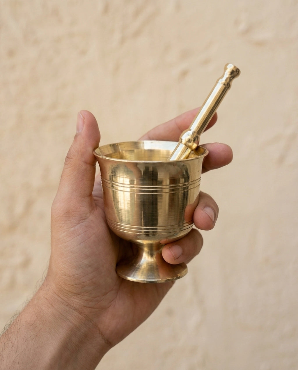 Bir elde tutulan, yatay çizgi detaylı sarı pirinç havan ve ergonomik tokmak. - Gaziantep Bakırcılık