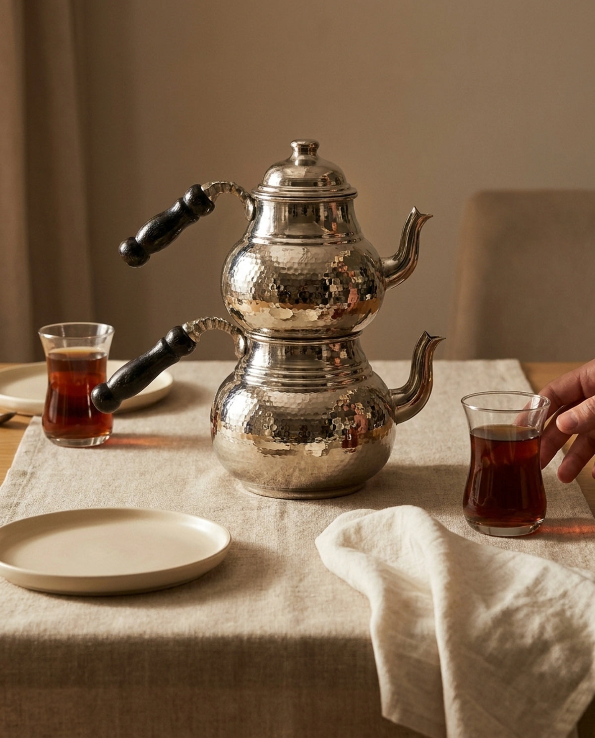 Örtülü ahşap masada çay bardakları ve servis tabaklarıyla birlikte sunulan dövme bakır çaydanlık. - Gaziantep Bakırcılık