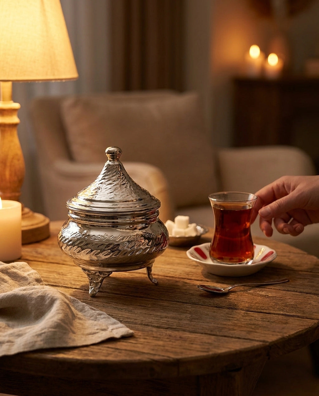 Loş ışıklı ahşap masada mum ve çay bardağı eşliğinde kalaylı şekerlik konsepti. - Gaziantep Bakırcılık