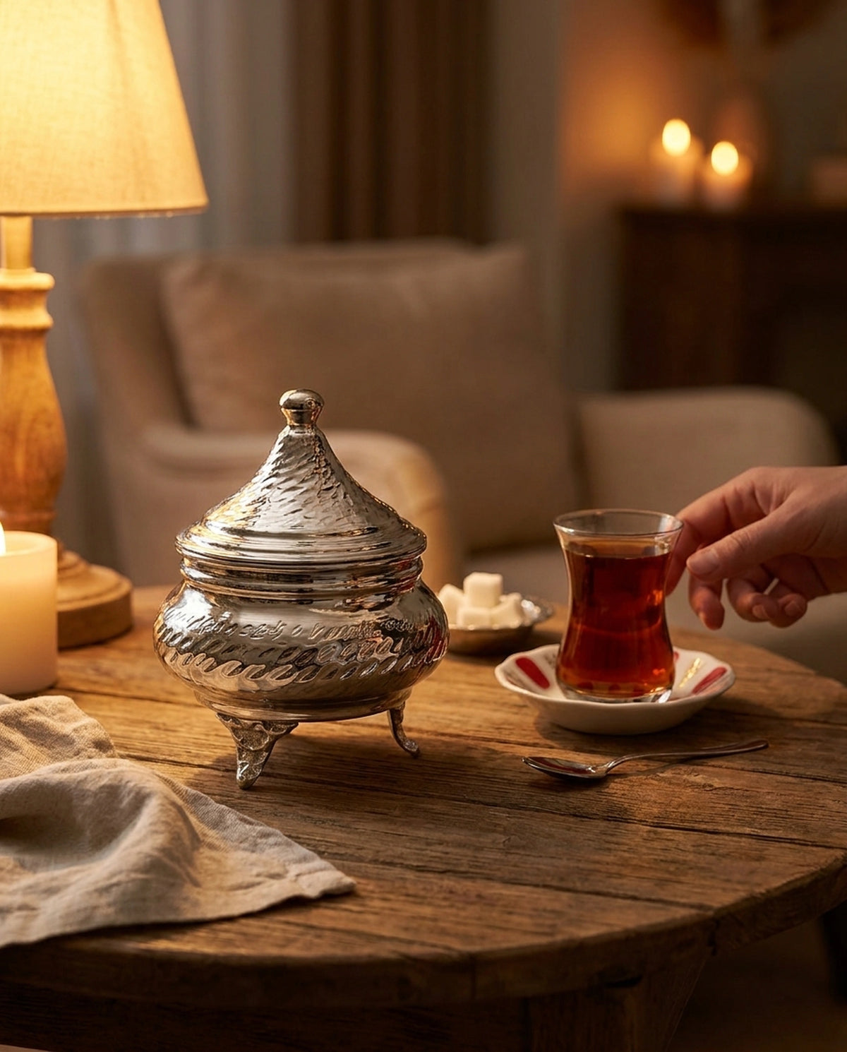 Loş ışıklı ahşap masada mum ve çay bardağı eşliğinde kalaylı şekerlik konsepti. - Gaziantep Bakırcılık