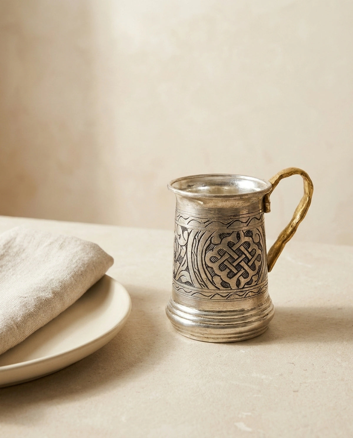 Keten peçeteli tabağın yanında duran, el işçiliği motifli bakır ayran bardağı. - Gaziantep Bakırcılık