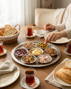 Şık sofrada işlemeli kâseden zeytin alan bir kişinin el görünümü. - Gaziantep Bakırcılık