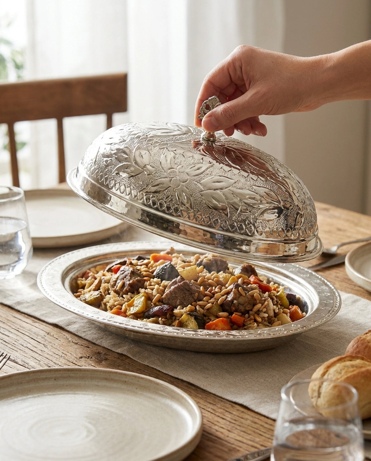 Etli pilav dolu işlemeli bakır sunumluğun kapağını kulpundan tutarak kaldıran el. - Gaziantep Bakırcılık