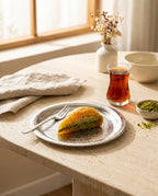 İşlemeli çelik sunum tabağında bir dilim fıstıklı baklava ve ince belli bardakta çay. - Gaziantep Bakırcılık