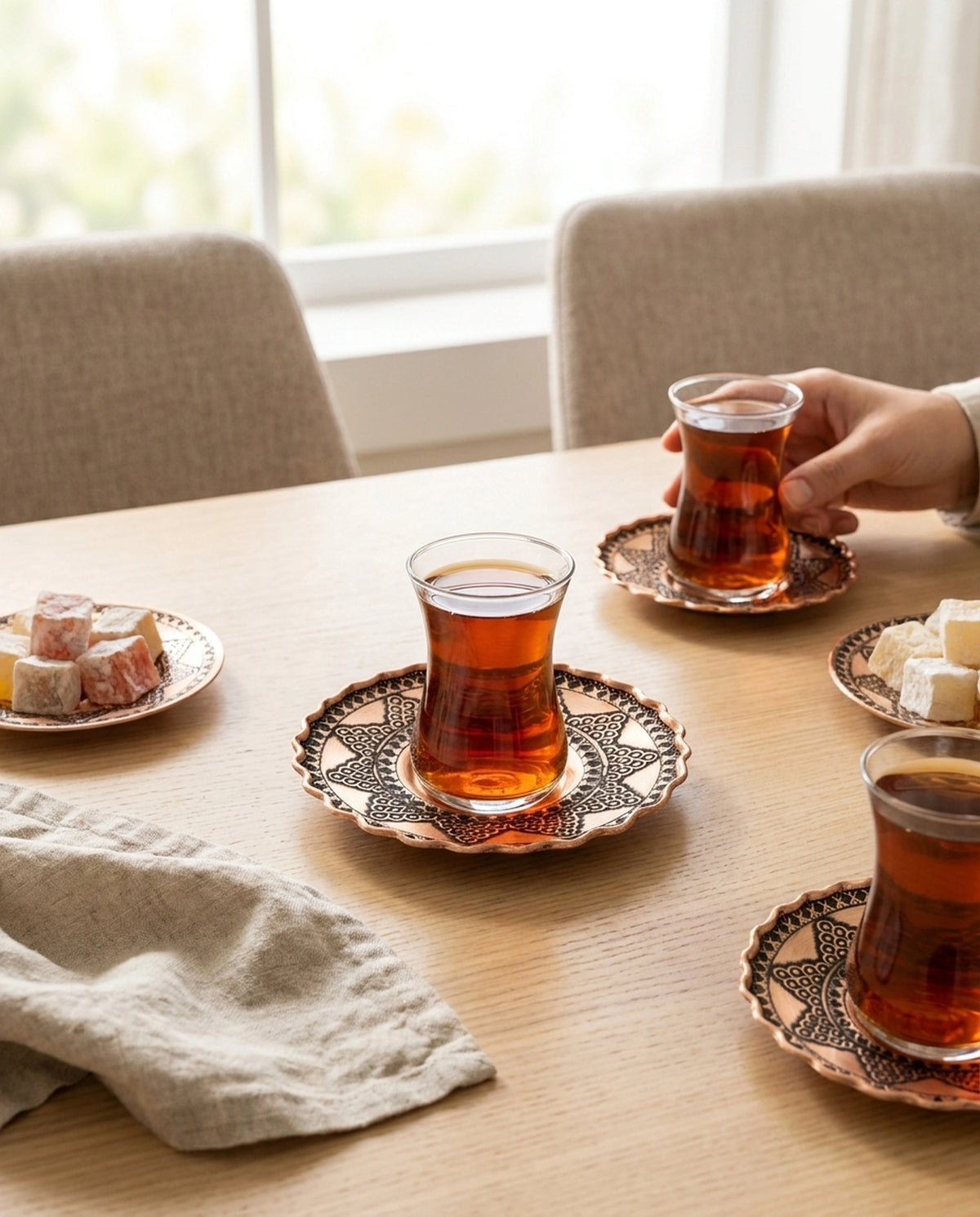 Ahşap masada çay bardakları, bakır altlıklar ve lokumlarla hazırlanmış çay saati sunumu - Gaziantep Bakırcılık