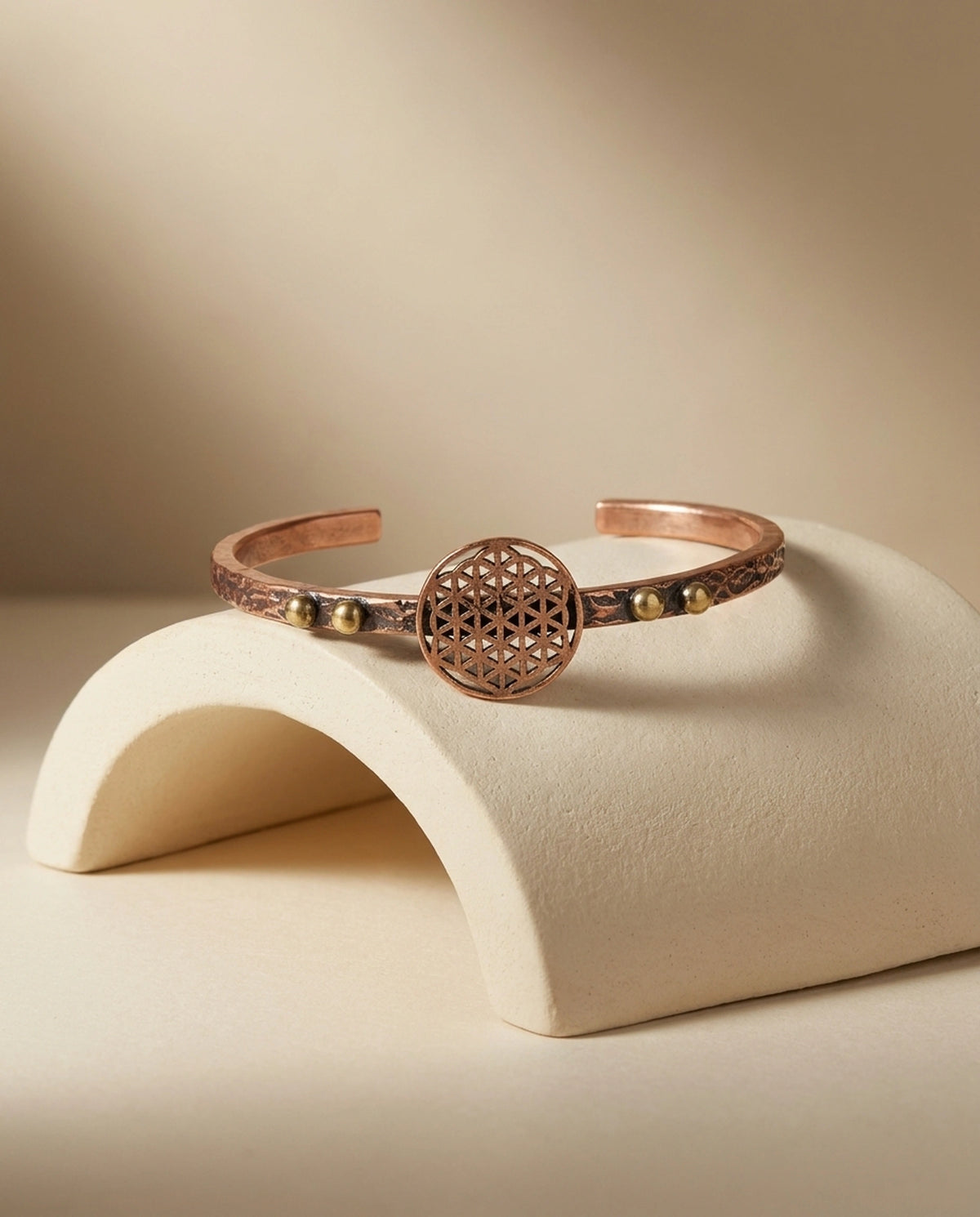 Kavisli seramik obje üzerinde yatay duran, geometrik yaşam çiçeği merkezli bakır bileklik. - Gaziantep Bakırcılık